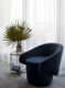 Round navy blue velvet chair with side table and fan leaves.